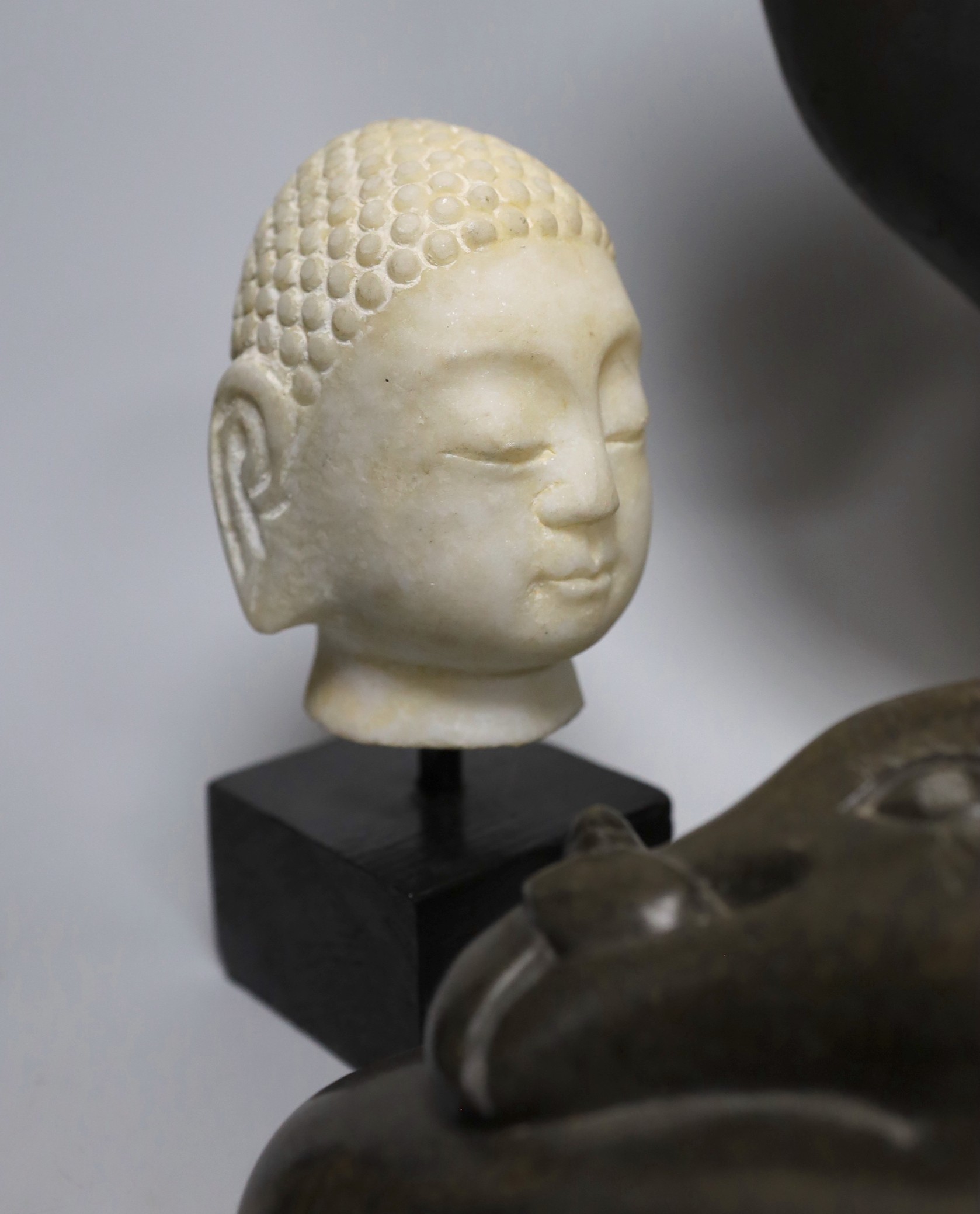 Three Inuit sculptures, a mask on stand and buddhist head, mask 39cms high